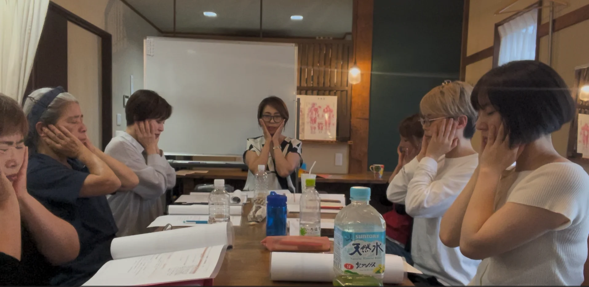 受講生が自分の顔に手を当ててセルフケアを実践している講座風景
